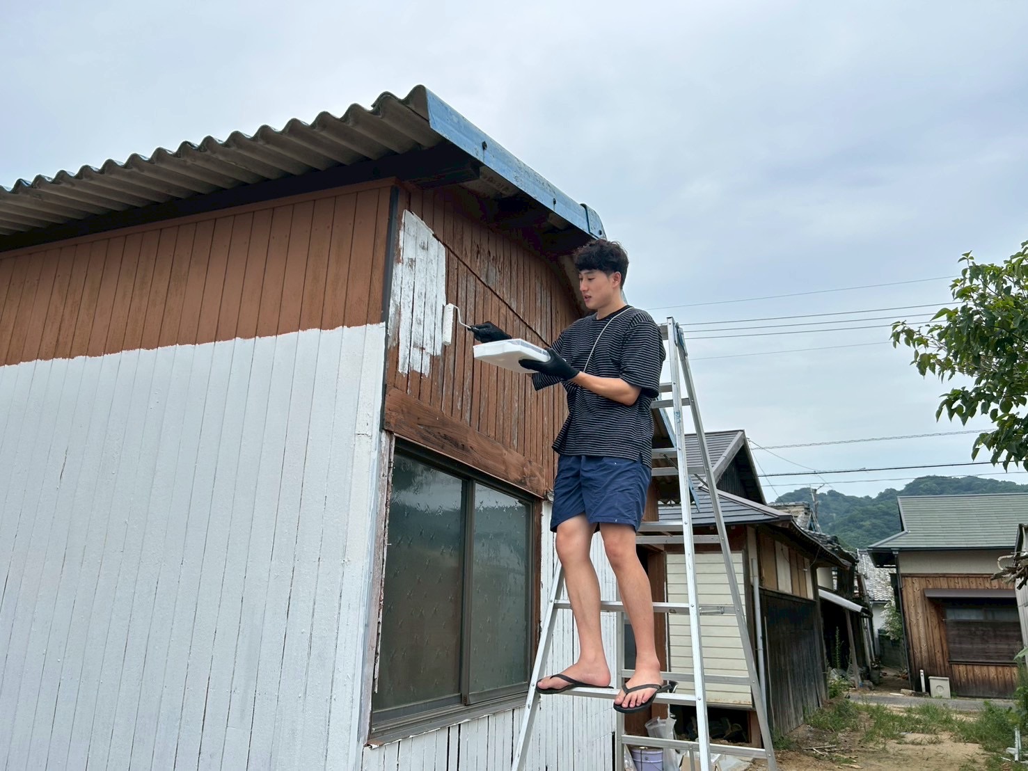 中島の古民家の外壁を手入れする矢野さとし